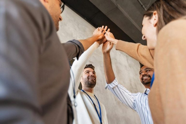 Diverse group of professionals celebrating with a group high-five, symbolising career growth after earning a Qualifi diploma